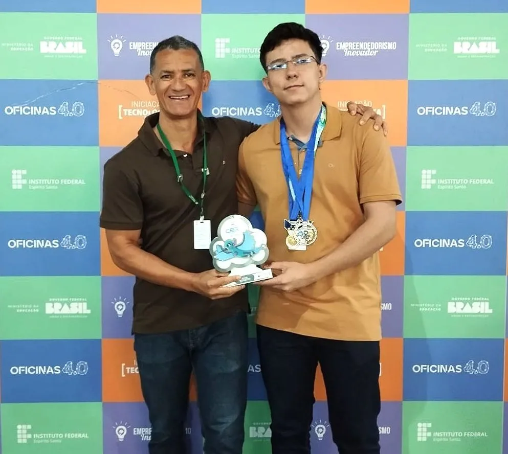 Estudante Maycon Santos e professor Marcos Pereira exibem troféu de 2º lugar na Olimpíada Brasileira de Robótica 2025